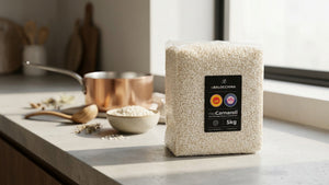 Confezione professionale di riso Carnaroli DOP da 5 kg su un piano di lavoro in cucina, con utensili e preparazione del risotto sullo sfondo