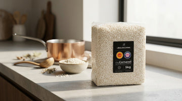 Confezione professionale di riso Carnaroli DOP da 5 kg su un piano di lavoro in cucina, con utensili e preparazione del risotto sullo sfondo