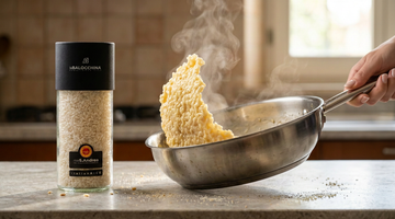 Vasetto di riso Sant’Andrea DOP accanto a una padella con risotto cremoso sollevata dal manico da una sola mano